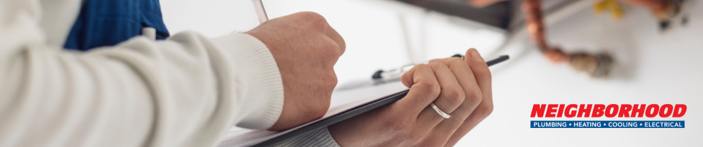 An HVAC professional during inspection, pointing out the furnace reset button to a client. 